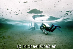 Ice divers, using cave dive techniques, proceeding to the... by Michael Grebler 